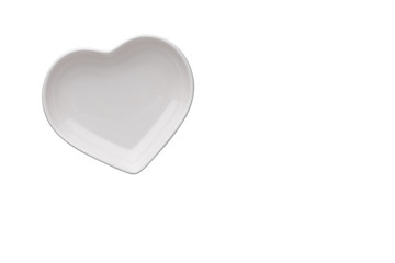 Ceramic glossy heart-shaped plate isolated on a white background. Stylish dishes. Saucer for Valentine's Day or wedding romantic menu design. Copy space. Minimalism. Close-up.
