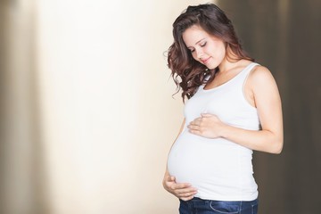 Pregnant young woman in white t shirt on bright background