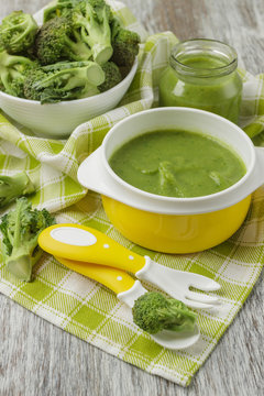 Fresh broccoli in the bowl, and portion of puree made from crushed broccoli, blurred background