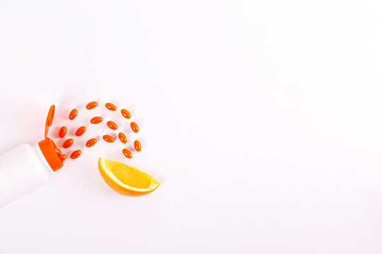 Conceptual image of open ontainer bottle of vitamin c with scattered orange pills on table. Top view, copy space, close up, background.