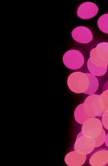 Vertical image of abstract blurred decorated lighting in vivid pink color gradations on black background 