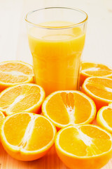 Glass of freshly pressed orange juice with sliced orange halfs