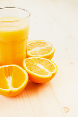Glass of freshly pressed orange juice with sliced orange halfs
