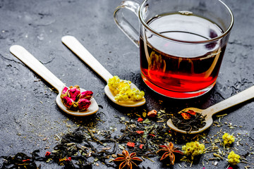 Teacup and herbs on dark stone background