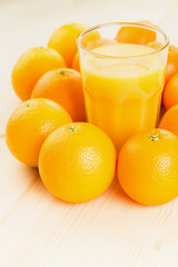 Fototapeta na wymiar Glass of freshly pressed orange juice with oranges