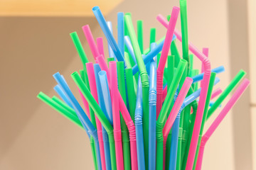 Top of several drinking straws made of plastic with different colors with blurred background.
