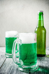 St. Patrick's day concept, two glasses and bottle with cold fresh cold green beer on wooden table, bar counter Background for St. Patrick's day and Oktoberfest menu. Copy space