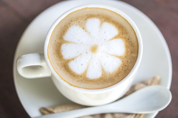 closeup cup of hot coffee latte flower art on wooden table at cafe shop 