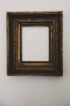 Close up of empty gilded antique picture frame on grey wall.