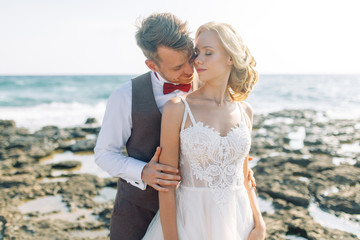 Fototapeta na wymiar Wedding photo shoot on the beach. Couple at sunset walks and hugs, laughs and kisses.
