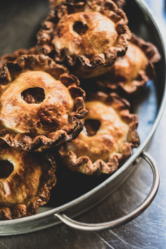 High angle close up of freshly baked raised Pork Pies on a metal tray.