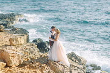 Wedding photo shoot on the beach. Couple at sunset walks and hugs, laughs and kisses.