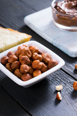 hazelnut cream sandwich breakfast and ingredients on white cutting board, black wooden table background