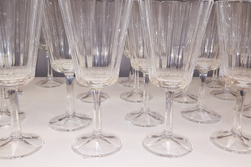 lot of empty clean glasses in shelf above a bar rack in restaurant
