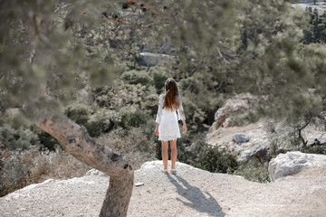 Naklejka premium Girl in white dress standing at the cliff