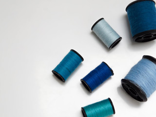 Blue spools of thread on white background with copy space
