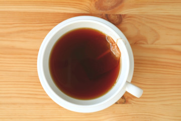 Top view of freshly brewed hot tea with tea bag served on wooden table 