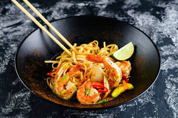 Stir fry noodles with vegetables and seafoods in black bowl
