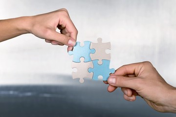 Human hands joining puzzle parts on background