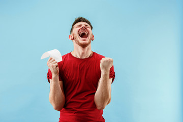Young boy with a surprised happy expression bet slip on blue studio background. Human facial...