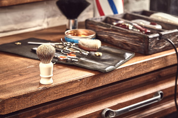 Hairdresser tools on wooden background. Top view on wooden table with scissors, comb, hairbrushes and hairclips, trimmer.