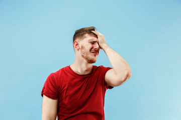 Naklejka premium Young boy with a surprised unhappy failure expression bet slip on blue studio background. Human facial emotions and betting concept. Trendy colors