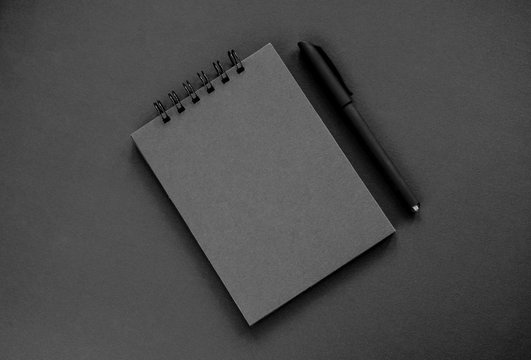 A black sketchpad, a black pen