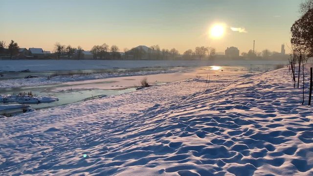 Frozen river covere by the snow. Sunset time. Winter