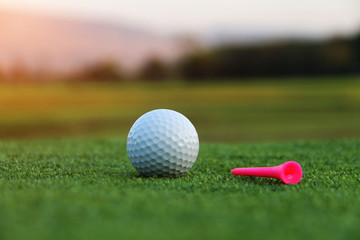 Golf ball and tee in beautiful golf course at sunset background.