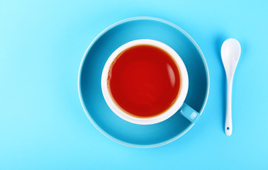 Blue cup of black red tea over blue background