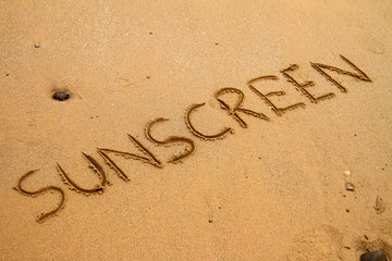 The word sunscreen drawn in sand at the beach