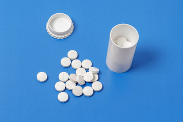 White tablets and bottle for tablets on blue background