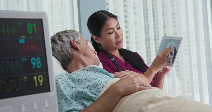 Doctor explaining brain scans to senior patient in hospital bed using tablet