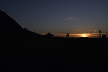 Fototapeta na wymiar Silhueta de horizonte com colina e pôr-do-sol