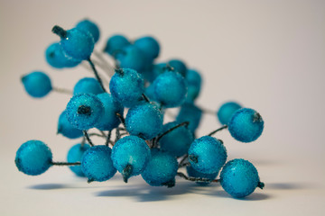 Texture. White background. Winter. An artificial branch of blue berries in hoarfrost. Dew drops. A decor for the house.