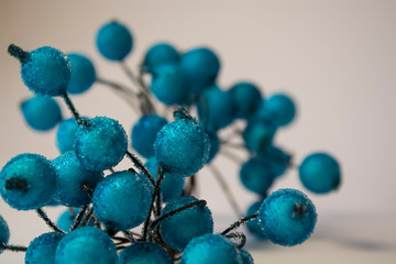 Texture. White background. Winter. An artificial branch of blue berries in hoarfrost. Dew drops. A decor for the house.