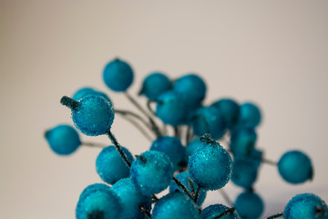 Texture. White background. Winter. An artificial branch of blue berries in hoarfrost. Dew drops. A decor for the house.