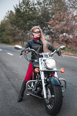 Plakat Beautiful biker woman posing outdoor with motorcycle on the road. 