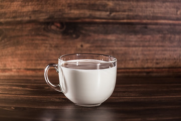 transparent bowl with milk on a wooden background