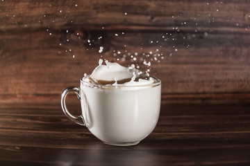 transparent bowl with milk on a wooden background with splashes