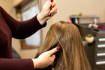 Fototapeta premium Stylist preparing brunette woman's hair for a color and highlight process