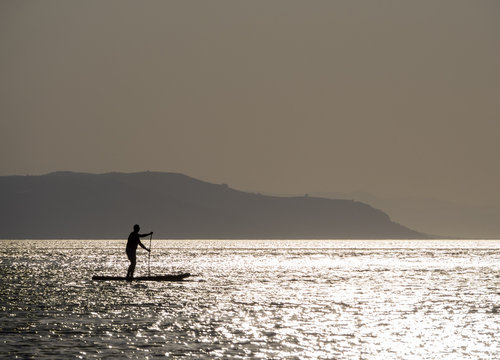 SUP Surfing at sunset in the Aegean Sea in Greece - Powered by Adobe