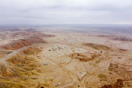 Desert in California with vehicles parked at a cliff, seen from the sky.