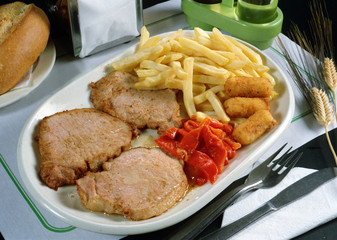 Plato con tres cortes de lomo a la plancha pimientos asados, tres croquetas de pollo y patatas fritas.