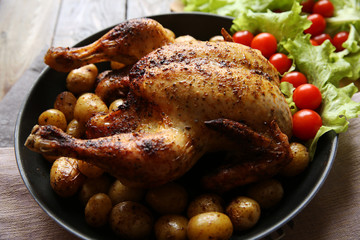 roasted chicken with potatoes on the wooden table