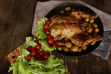 grilled chicken with vegetables: potatoes, tomatoes and lettuce on the wooden table