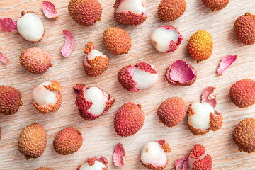 Peeled lychee fruit with peel on wooden table
