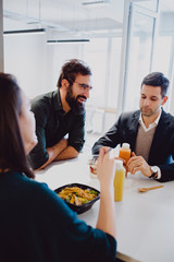 Man smiling in the office cafeteria while colleagues eating