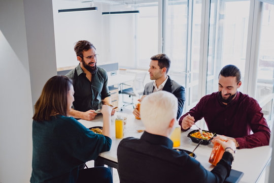 Smiling coworkers eating at the table in the office
