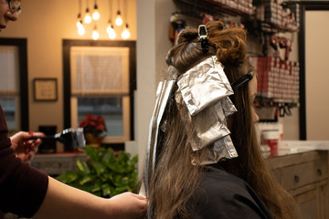 Side view of hair color and highlight process with foils for education or website